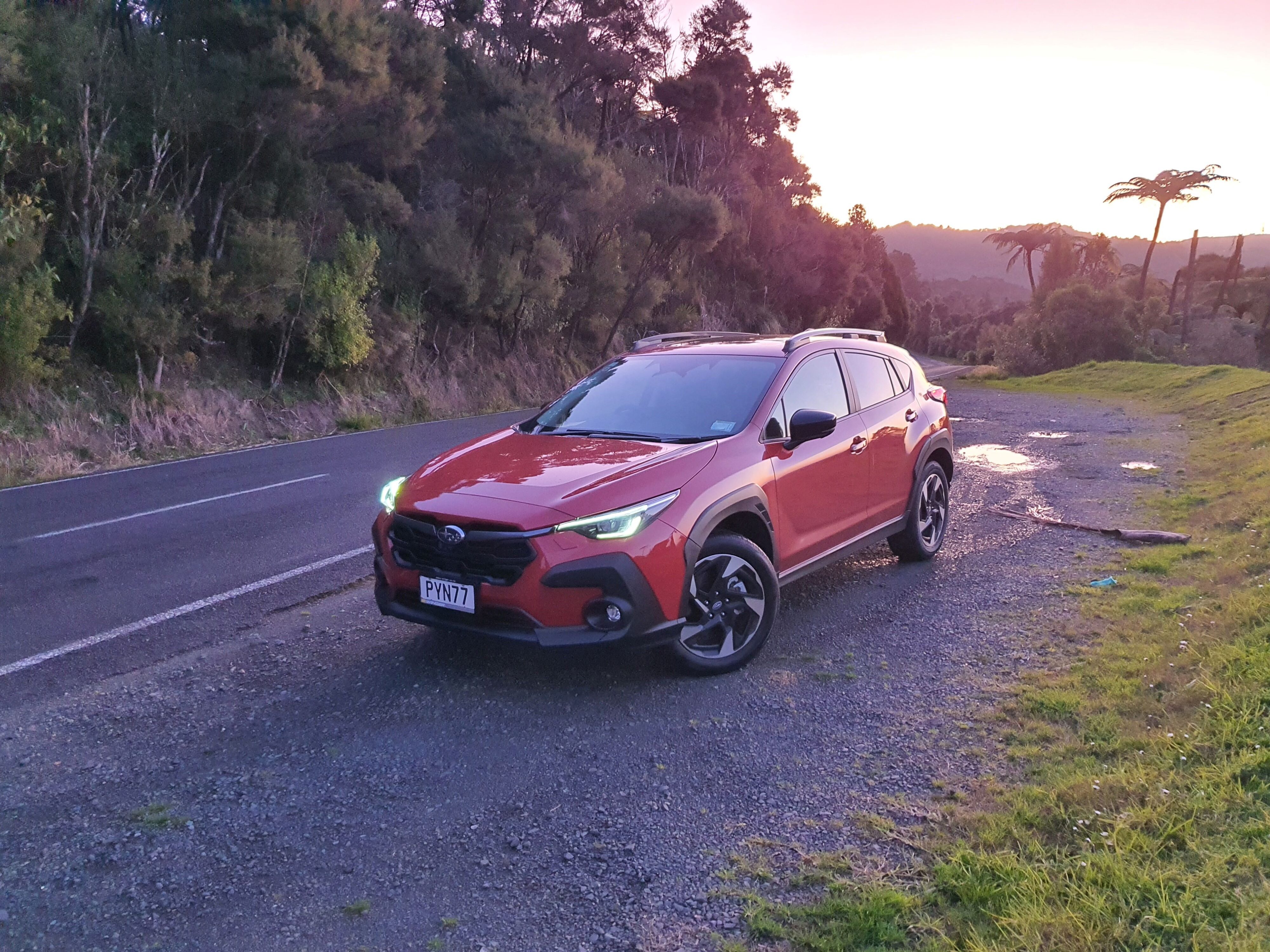 Front three quarters view of an orange Subaru Crosstrek at sunset.