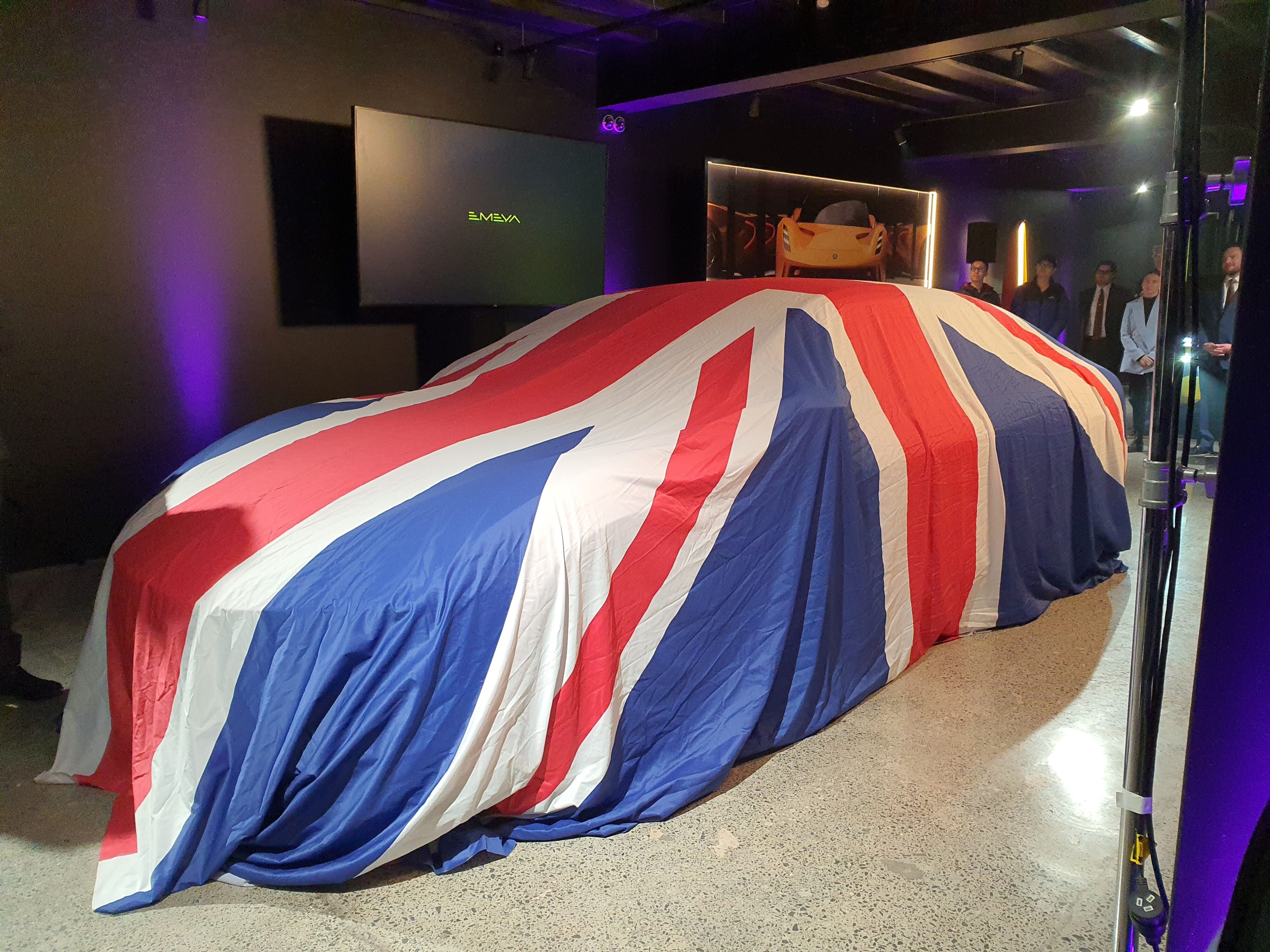 A 2024 Lotus Emeya S under the cover of a large Union Jack at Lotus Auckland.