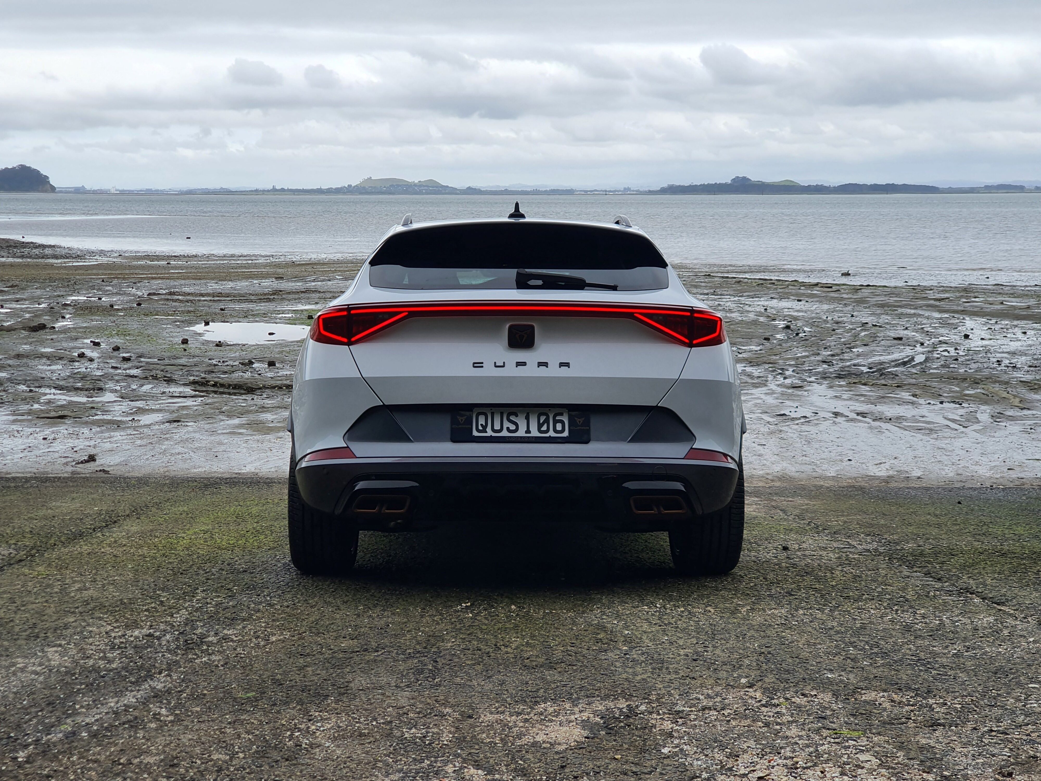 Straight on view of the rear of a 2024 Cupra Formentor V e-Hybrid in white on a boat ramp.