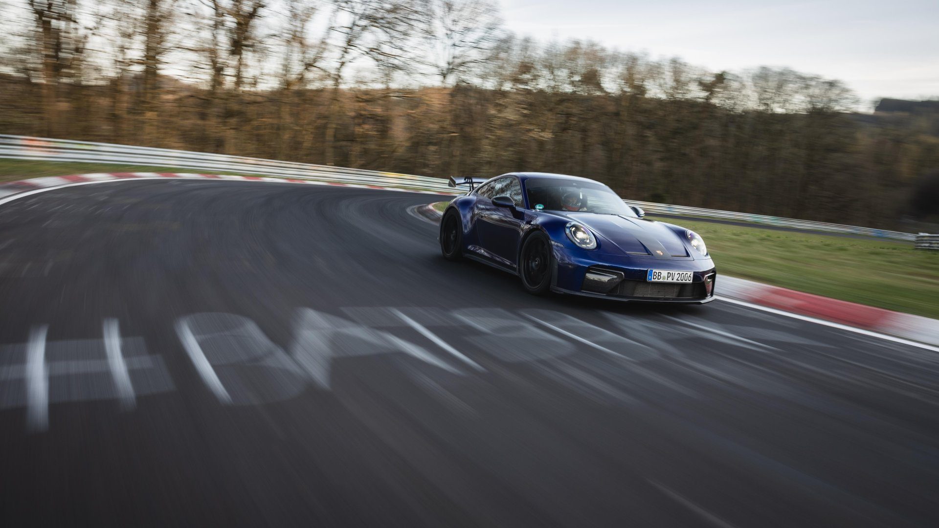 A photo of a dark blue manual 2025 Porsche 911 GT3 racing around the Nurburgring.