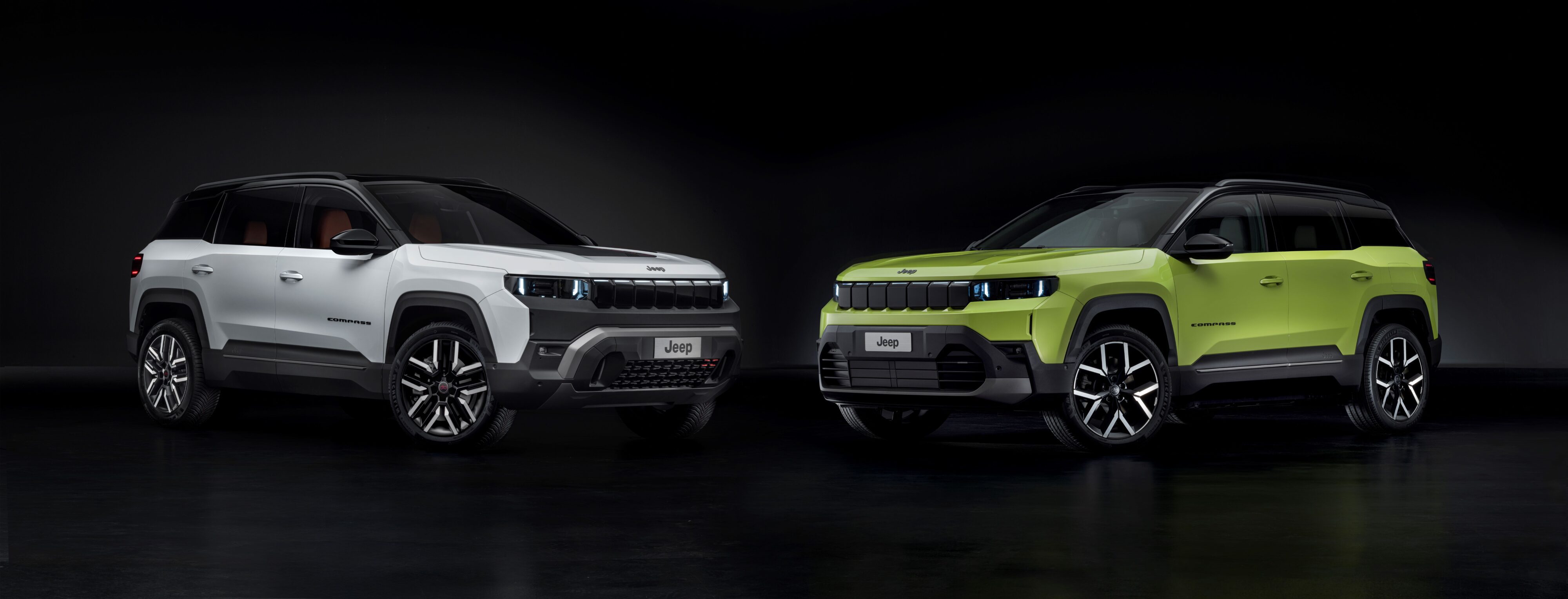 A frontal view of two new Jeep Compass vehicles, the one on the left in white and the one on the right in green.