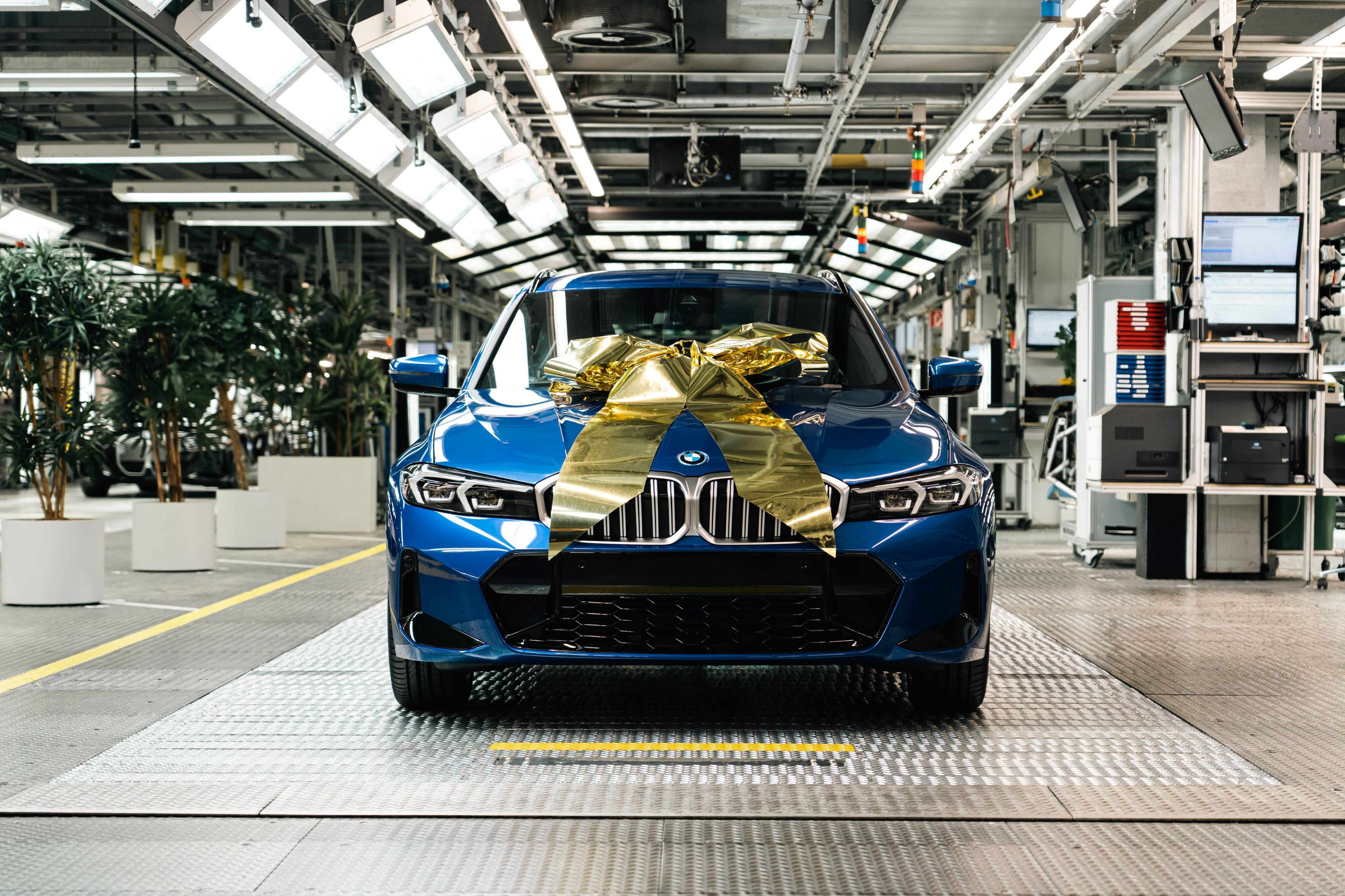 A photo of the three millionth BMW electrified vehicle rolling off the line in Munich. The special car is a blue BMW 330e Plug-in Hybrid Touring.