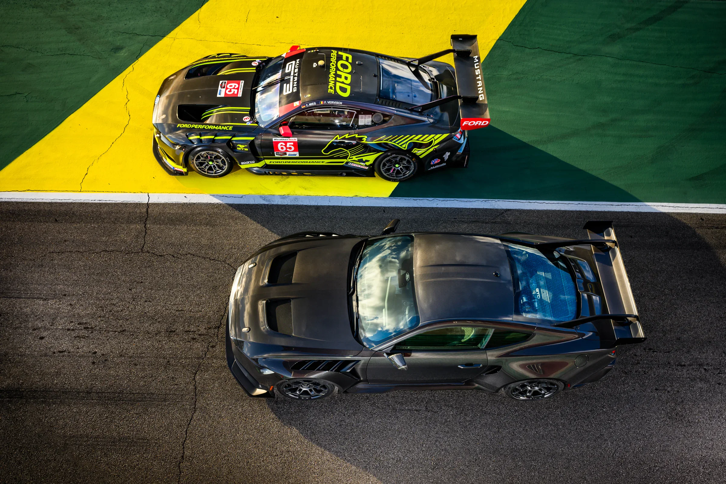 A photo of two racing spec Ford Mustangs side by side on a racetrack.