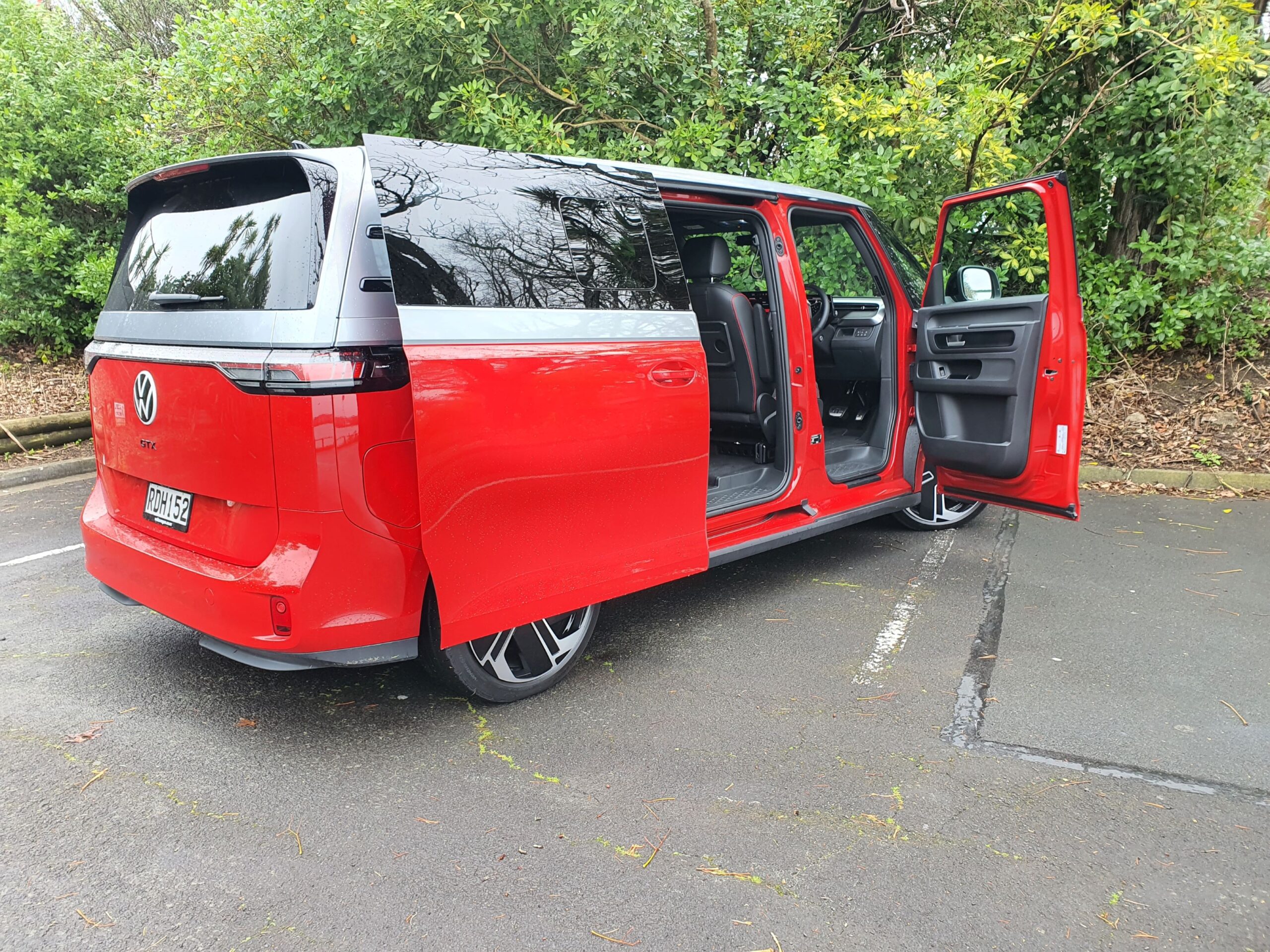 Rear three quarters view of a 2025 Volkswagen ID.Buzz GTX in red and silver with the doors open.