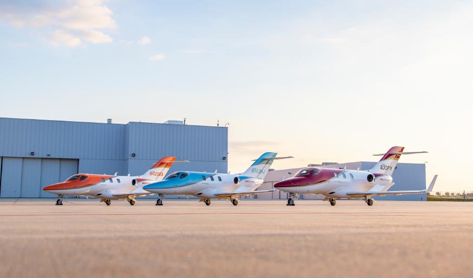 A photo of a lineup of HondaJets parked at an airport hangar.